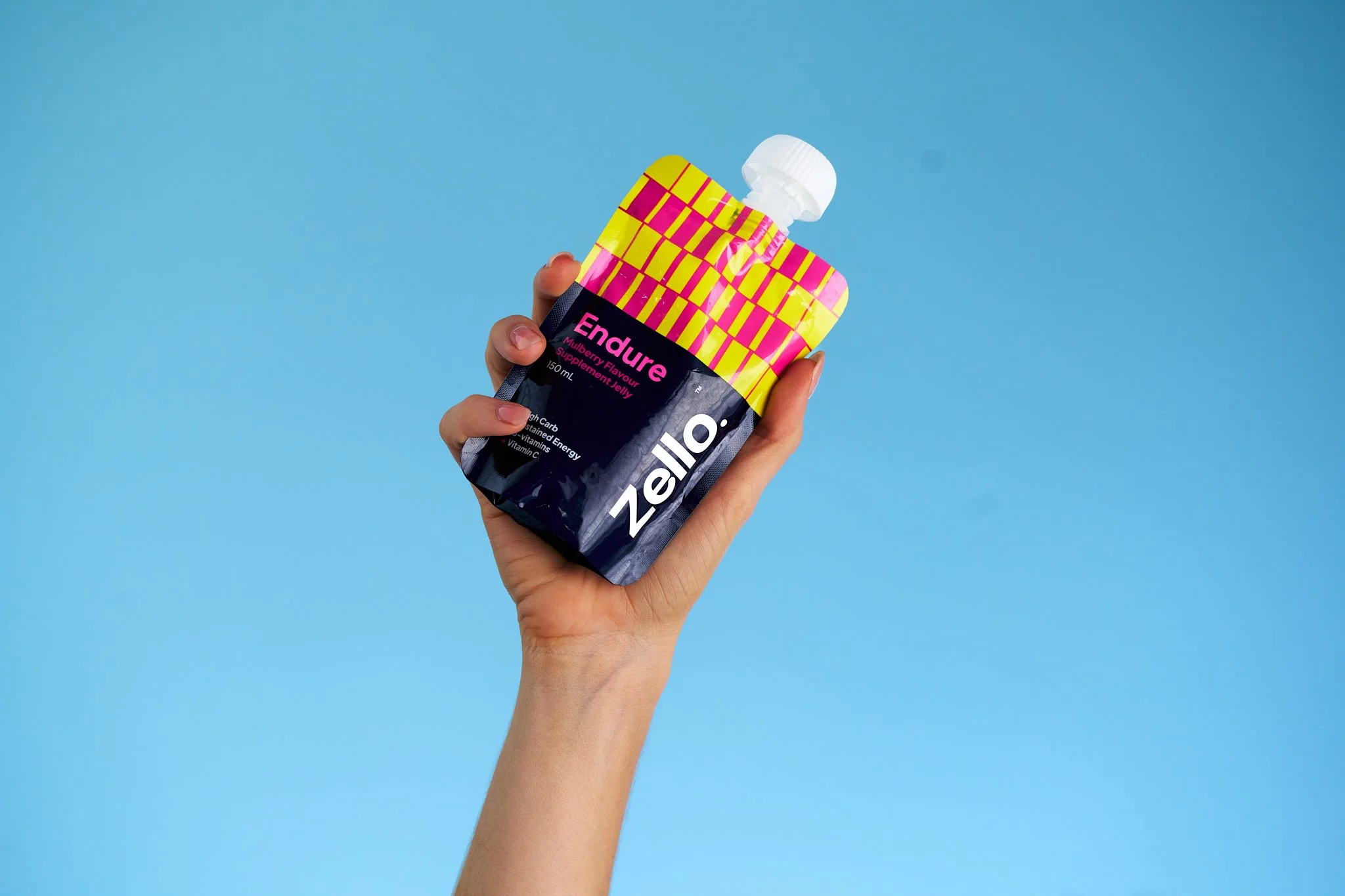 A person holding a Zeo Endure jelly supplement packet with a blue background.