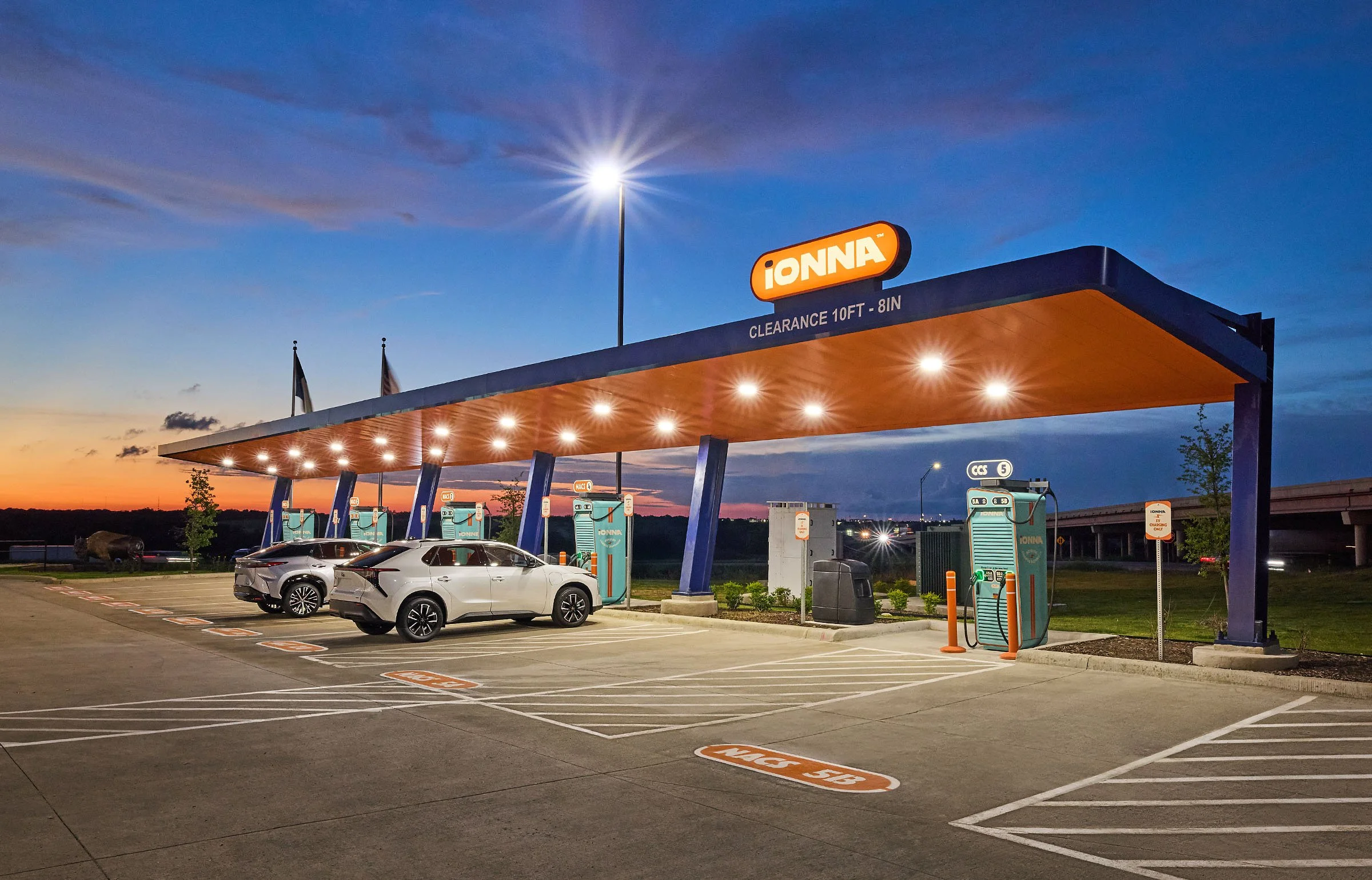 A Toyota and Lexus vehicle are parked at an iONNA charging station at dusk. 