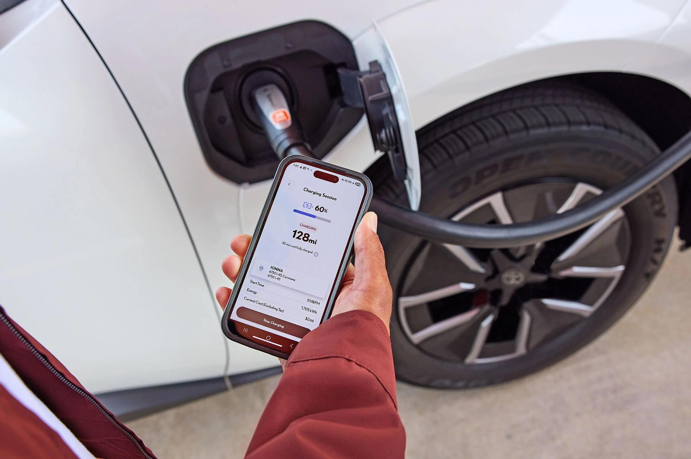 A man checks his phone to see the battery status of his Toyota electric car. 