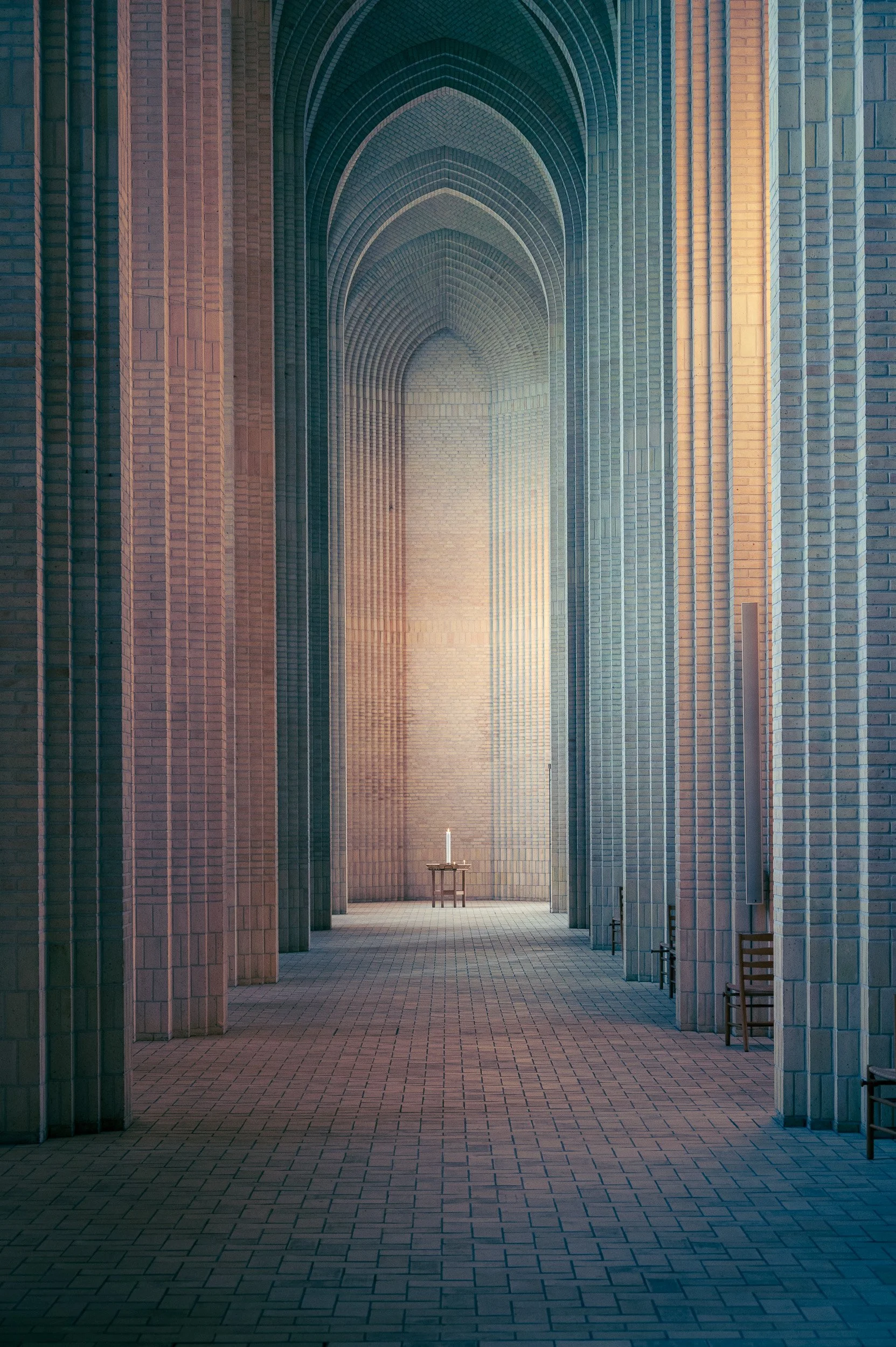 Symmetrical architectural interior of Grundtvig's Church in Copenhagen, capturing soft light on the soaring gothic brick pillars.