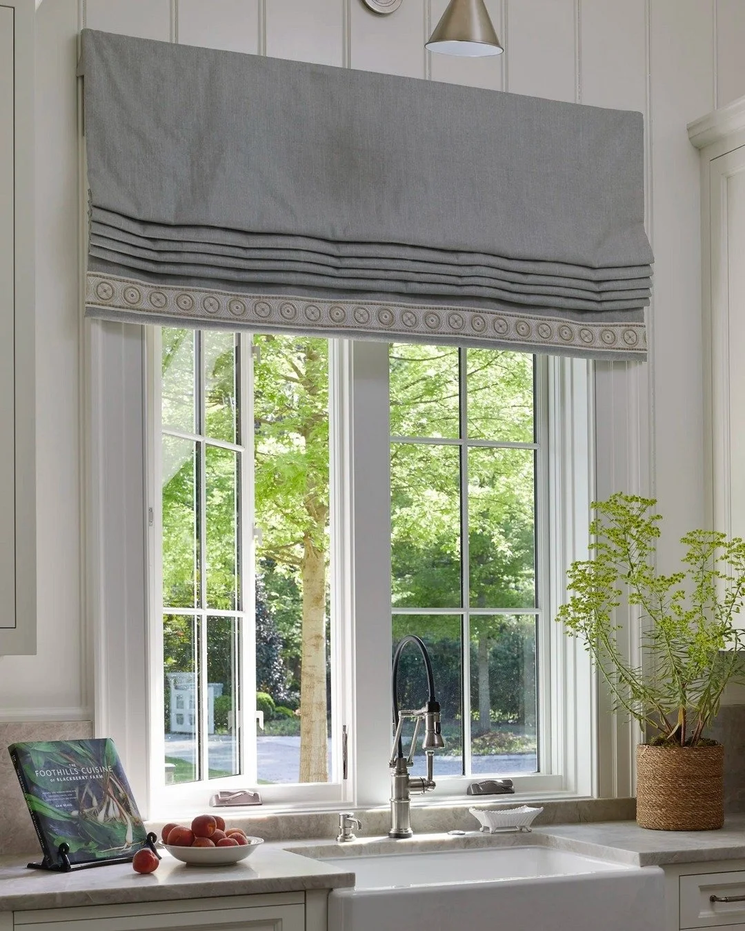 Early fall light streaming into a timeless scullery&mdash;from the tailored Roman shade to the classic farmhouse sink, this space blends elegance with effortless functionality. A serene backdrop for crisp mornings and chores are a little more enjoyab