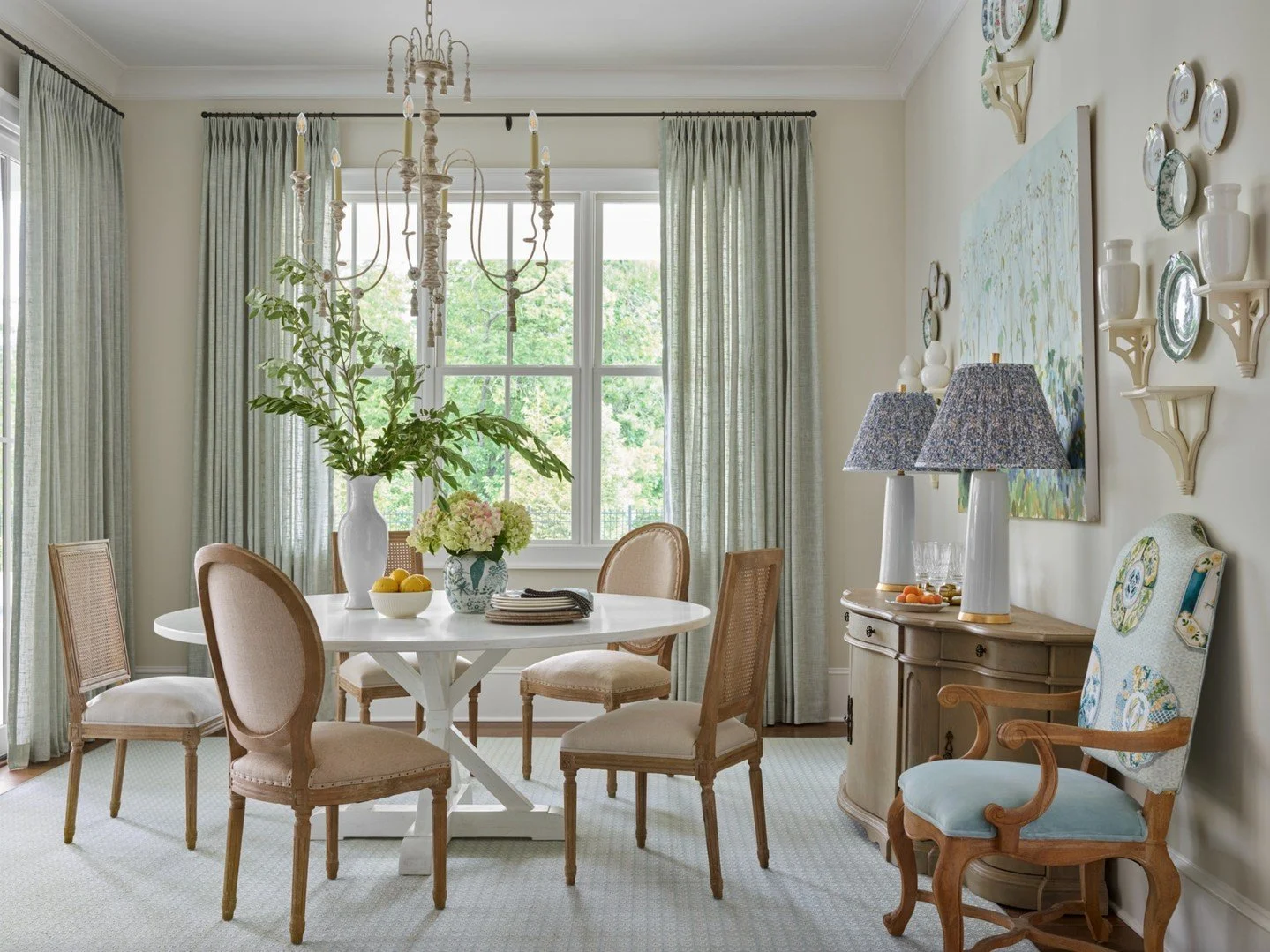 A welcoming breakfast room: soft drapery, French silhouettes, and a crisp pedestal table set the stage, while layered details&mdash; the patterned lamp shares and color from the drapery add layered color and textures.

📷 @emilyfollowillphotographer
