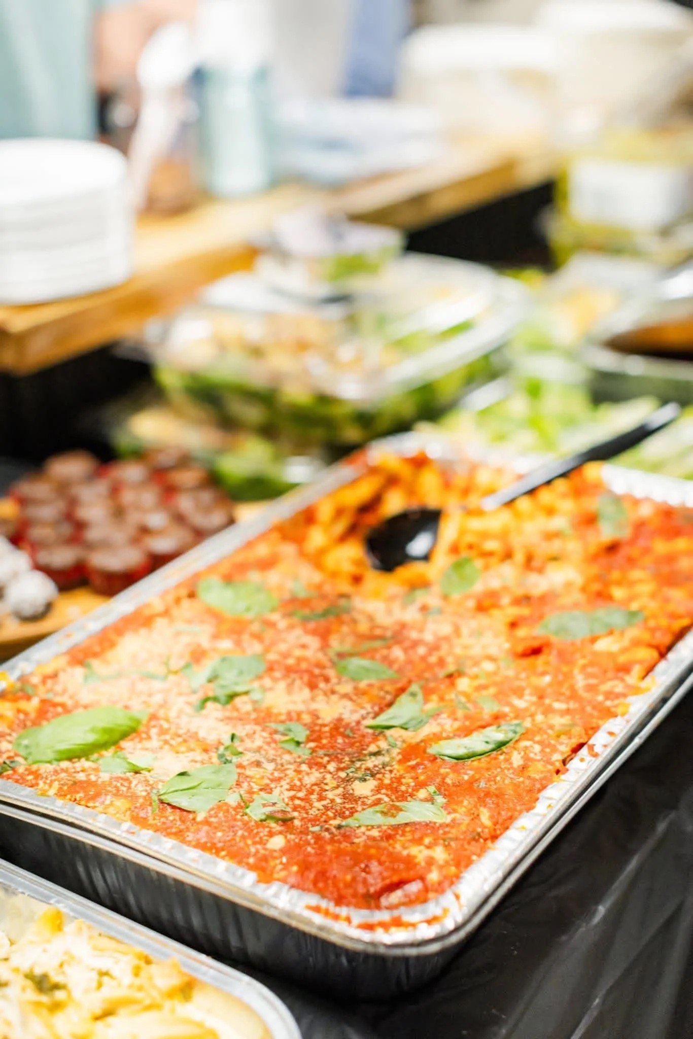 Full tray of baked pasta in red sauce topped with basil