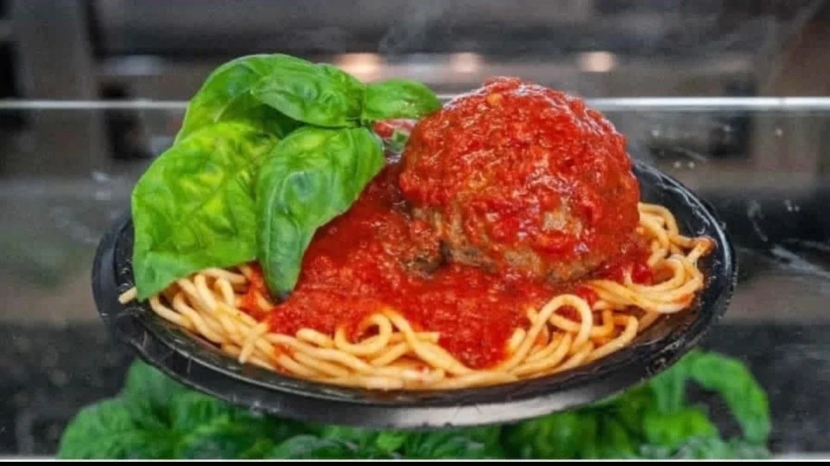 Spaghetti with a large meatball in marinara and fresh basil