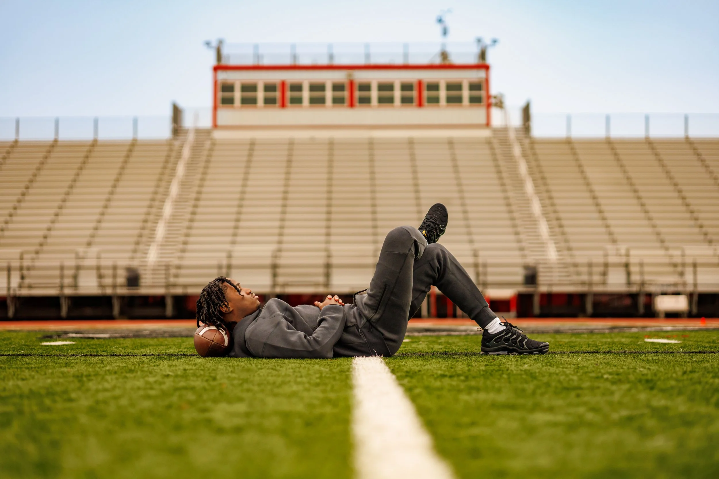 High school senior athlete relaxing on a football field during senior portrait session in south Mississippi.