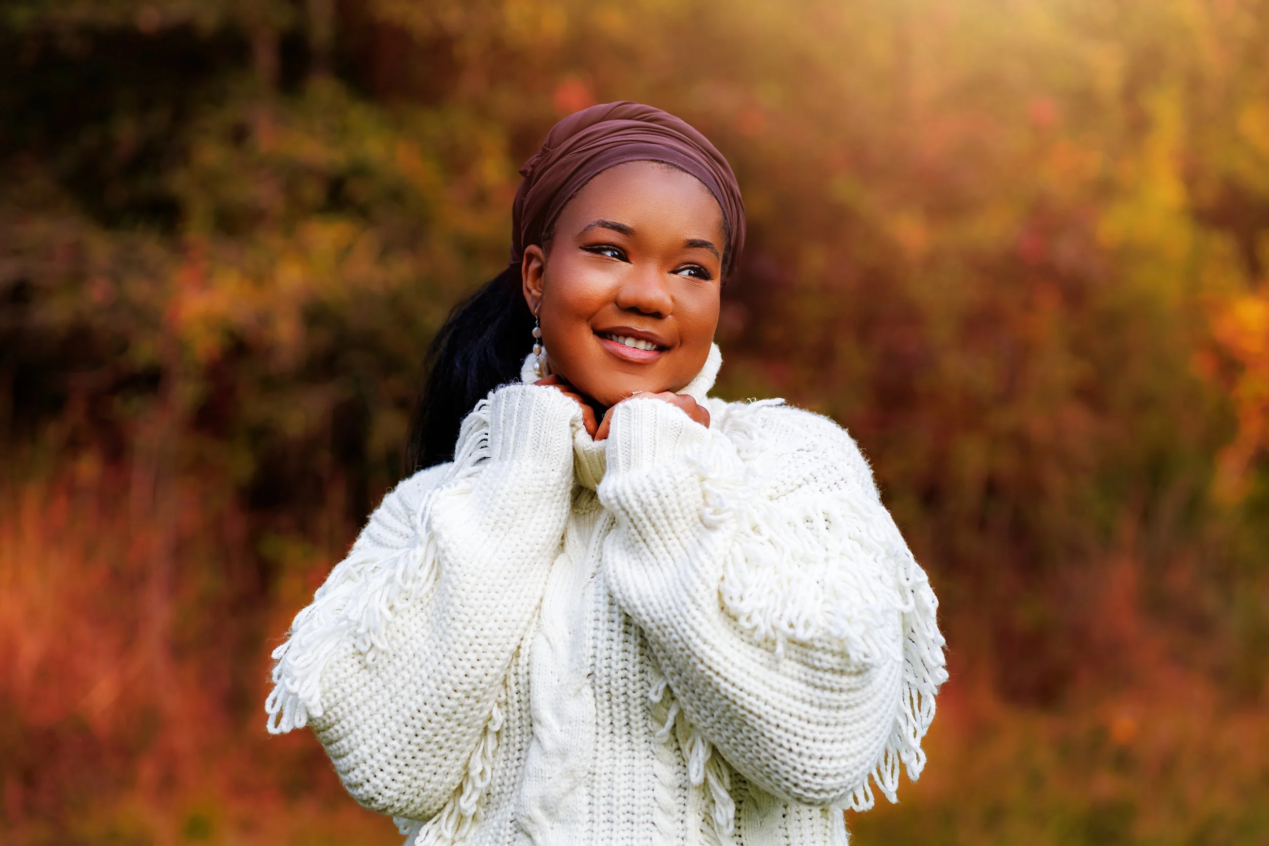 Women in cream sweater smiling during golden hour outdoor portrait session with Jackie Larkin Photography in South Mississippi.
