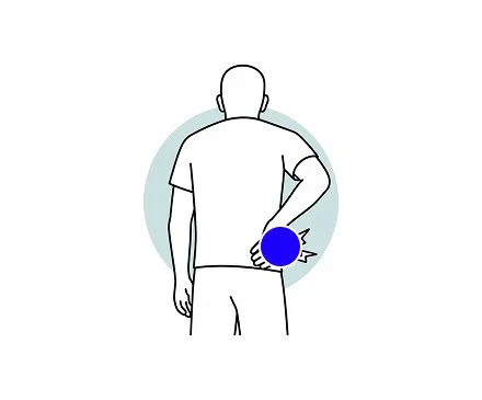 A person standing and holding their lower back with their right hand, indicating back or hip pain.