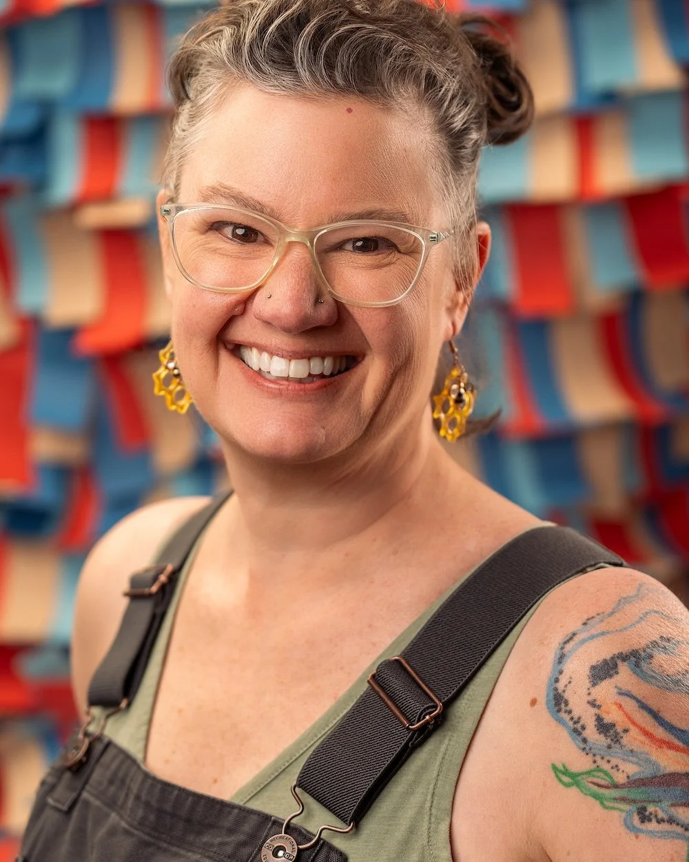 smiling white woman with pigtails and overalls in front of a mottled background