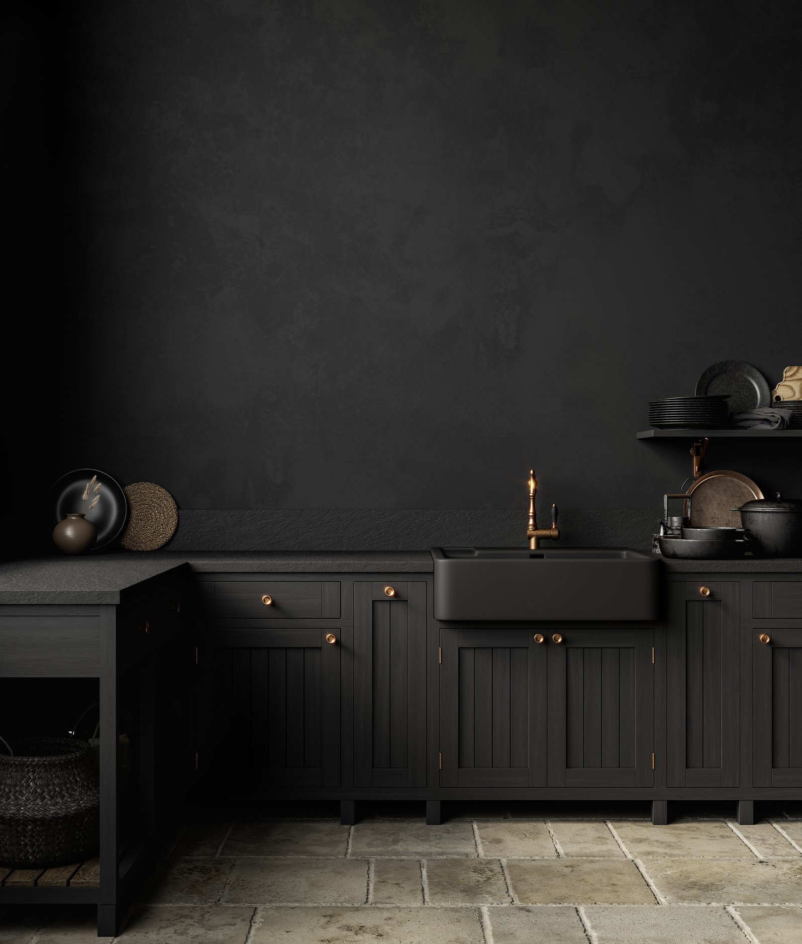 Dark grey kitchen with black cabinetry, brass handles, black countertops, black sink with brass faucet, shelves with black and grey dishes, decorative vases and woven baskets, and a stone tile floor.