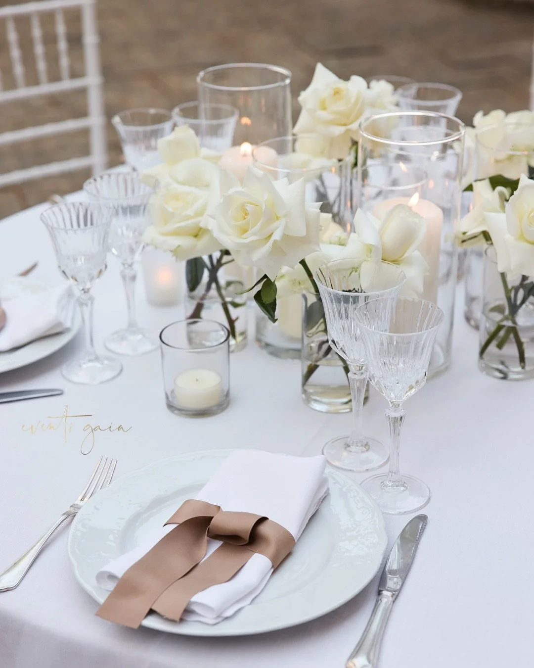 In the quiet embrace of an Italian courtyard, romance unfolds through design.
White roses bloom effortlessly amid the soft glow of candlelight, their delicate petals mirroring the architecture&rsquo;s timeless grace. The tablescape, a study in minima