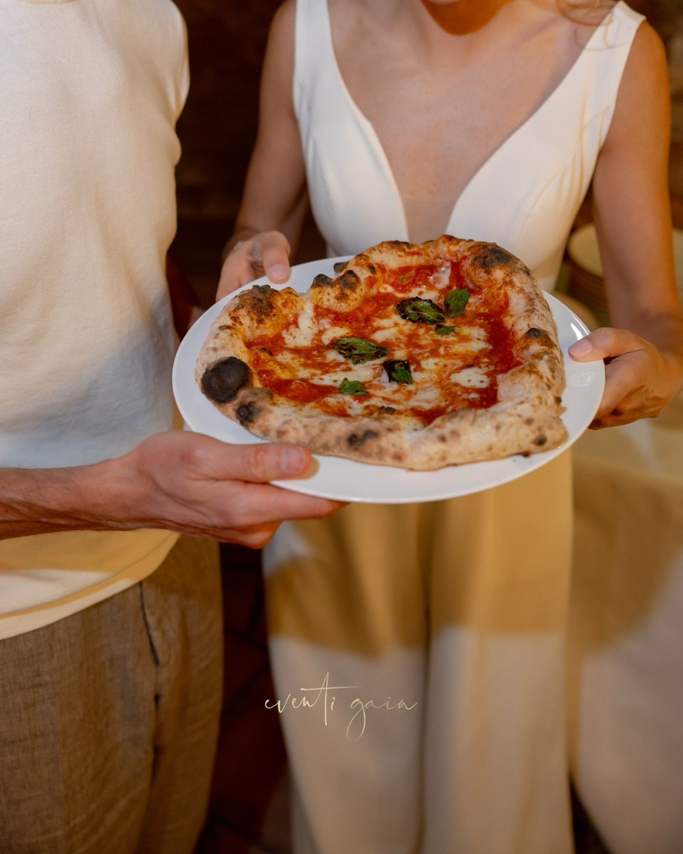 Somewhere between the laughter, the flour-dusted hands, and the glow of the Tuscan evening, the bride and groom shaped their own heart &mdash; literally. A handmade, heart-shaped pizza 🍕 &hearts;️ crafted together in the middle of the celebration, w