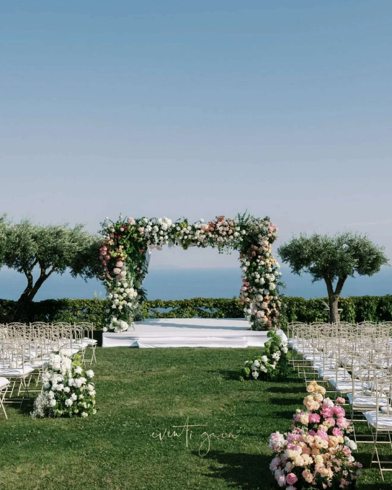 A floral masterpiece overlooking the endless blue of the Mediterranean. 🌸✨

An enchanting ceremony setting where lush garden-inspired florals, delicate shades of blush pink, ivory and soft peach, and elegant white draping come together to create a m