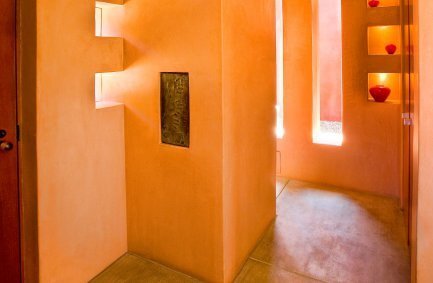 Cutout portal windows in thick earth colored walls bring light and shadows into the interior of our modern Mandeville Canyon home in Brentwood, Los Angeles