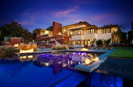 Fire features ring the outdoor pool at our Buckskin house modern Prairie style home