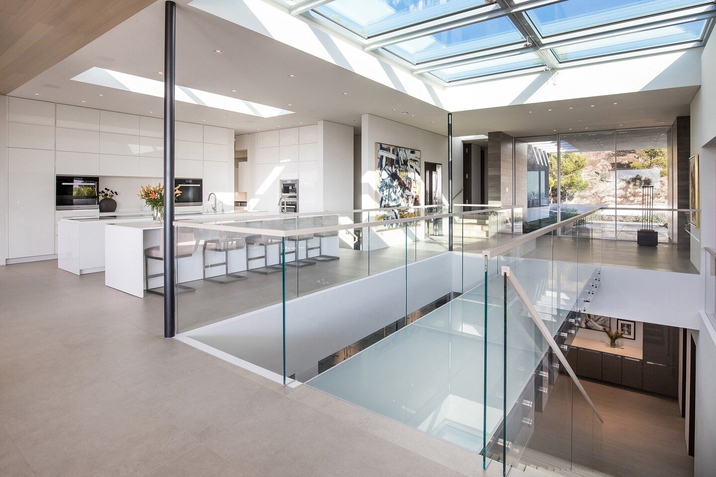 The bright light filled interior of our Trousdale House features skylights, an open volume atrium, glass walls, and a floating glass bridge. Photo by @jasonspethphoto