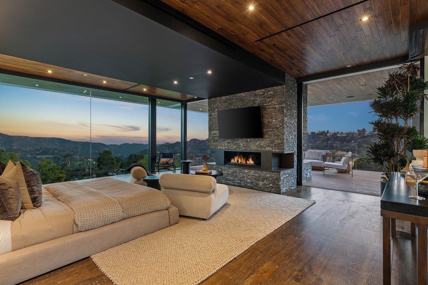 The luxury primary suite at our Benedict Canyon House, with floor to ceiling floating glass walls, and a private terrace with views. Photo by @mrbarcelo