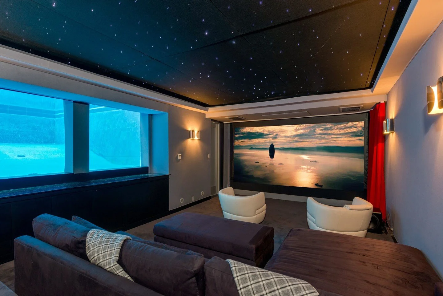 The modern home theater at our Hopen Place house in the Hollywood Hills, with underwater pool views that add an ethereal blue light to the custom room. Photo by Michael McNamara Shooting LA / @dwellmagazine