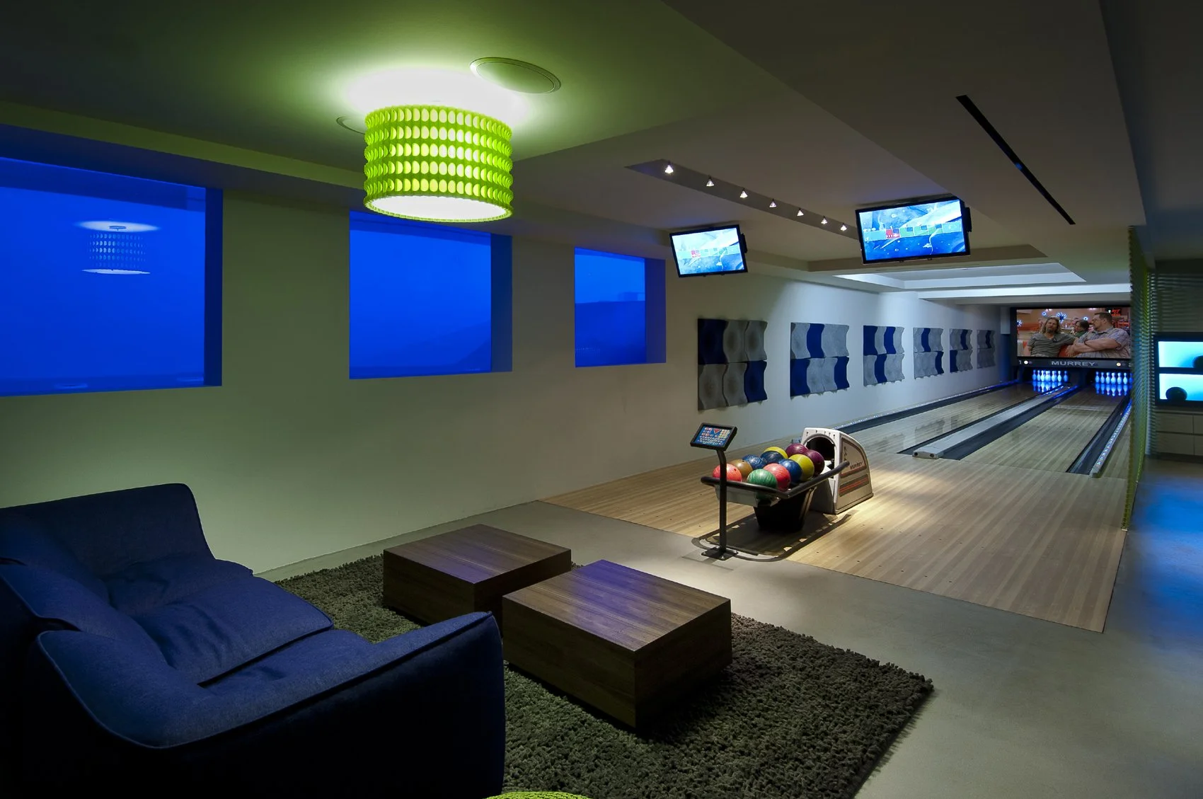 Modern home bowling alley with underwater windows and views into the adjacent pool, at Summit House, a luxury Beverly Hills house
