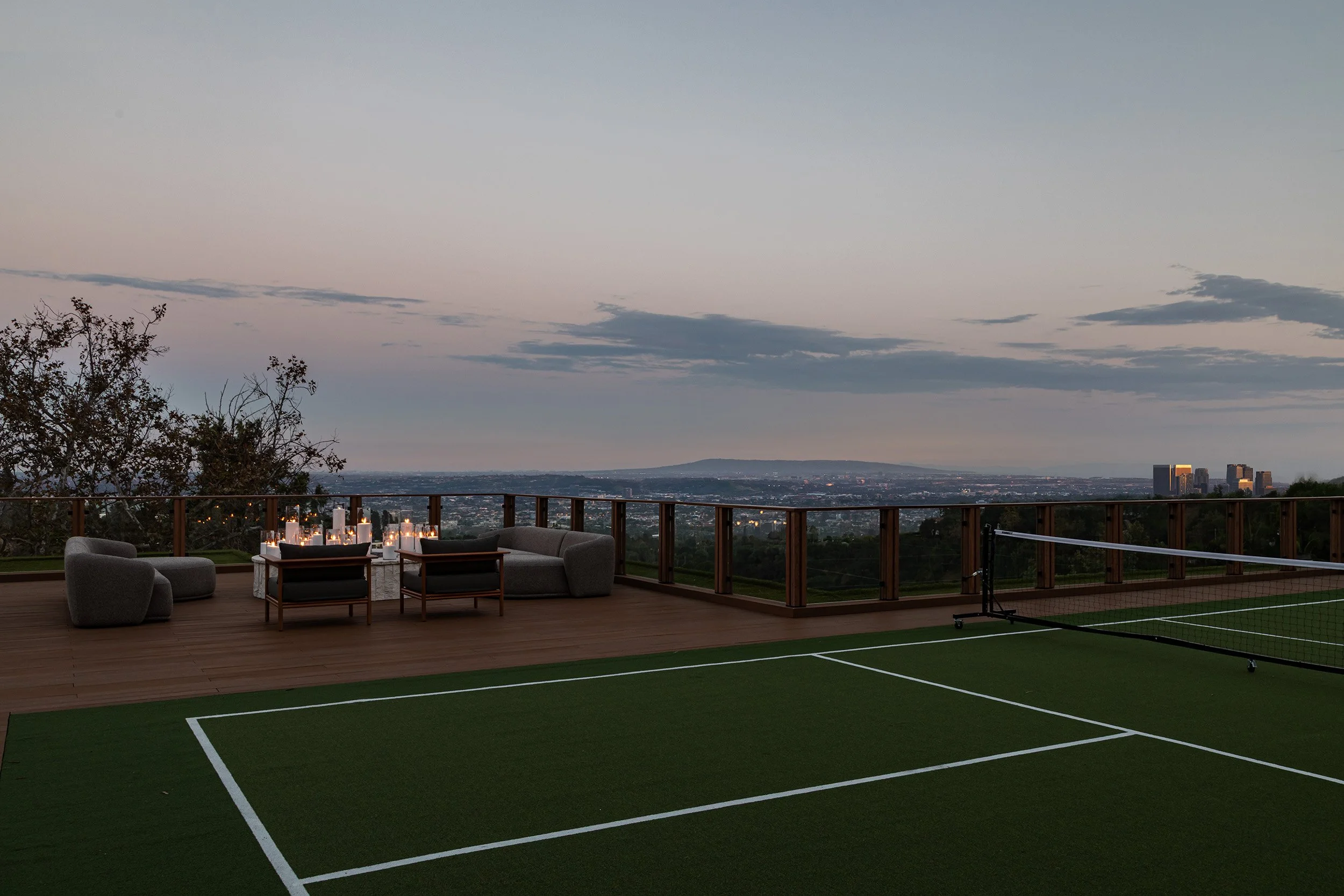 Franklin Canyon Beverly Hills luxury home rooftop tennis court at dusk with fire pit lounge & views