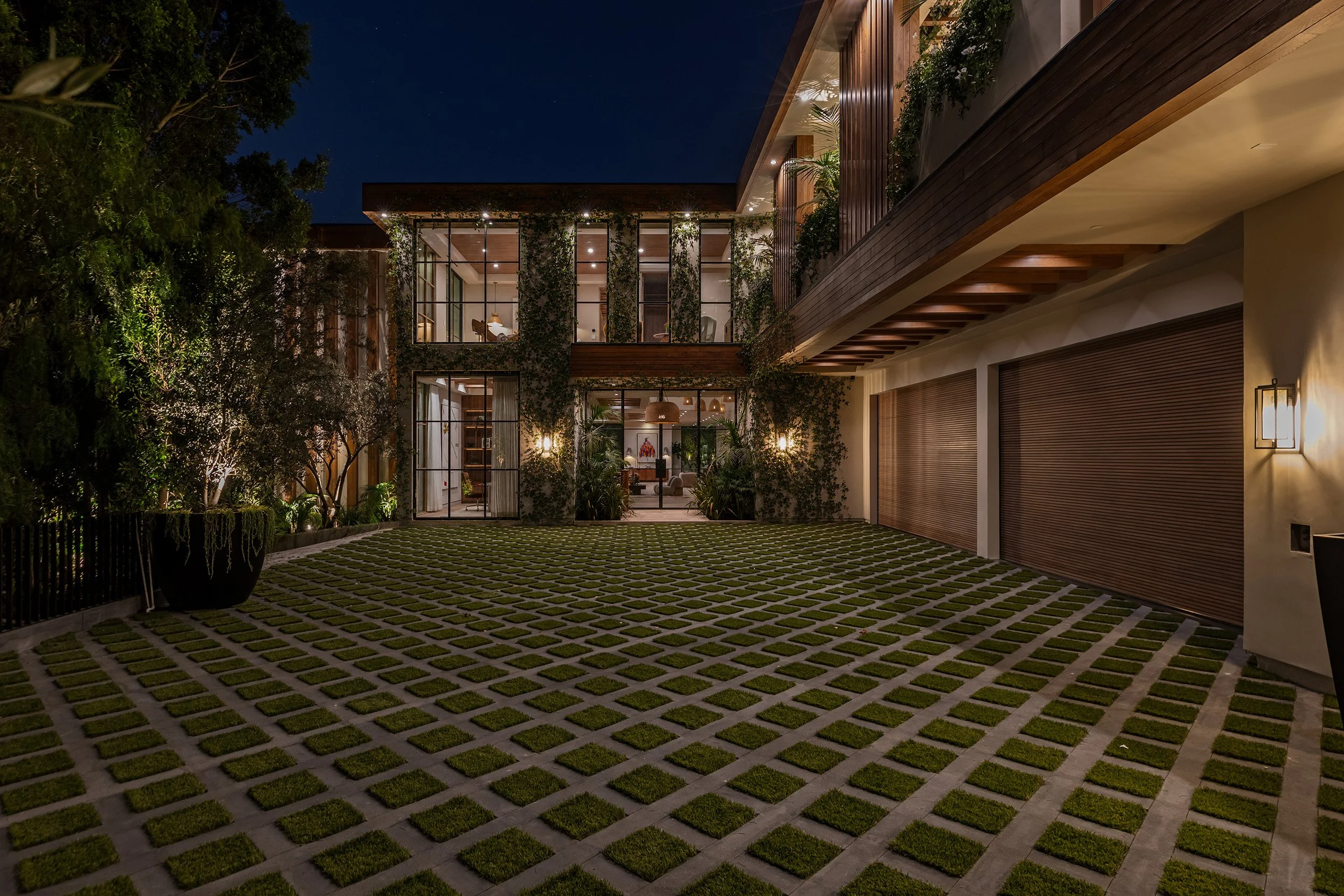 Franklin Canyon Beverly Hills luxury home exterior at night with modern design details & lush landscaping