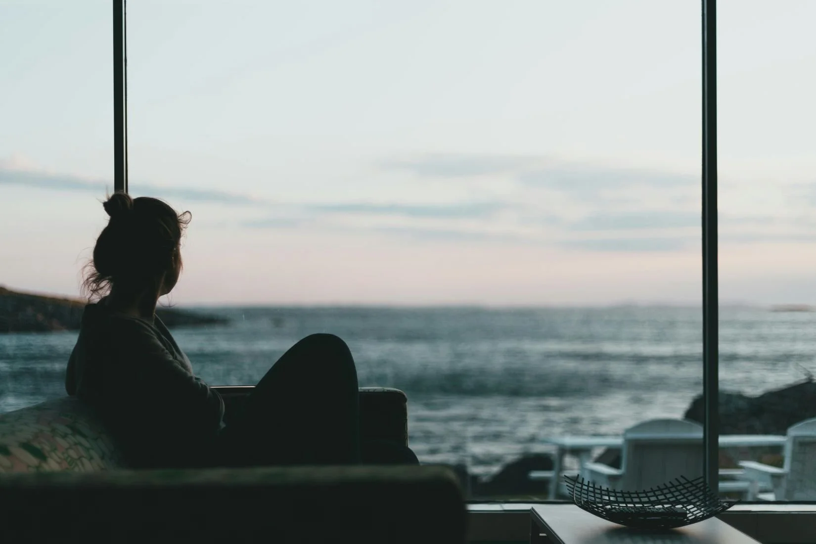 Woman looking at beach from indoors