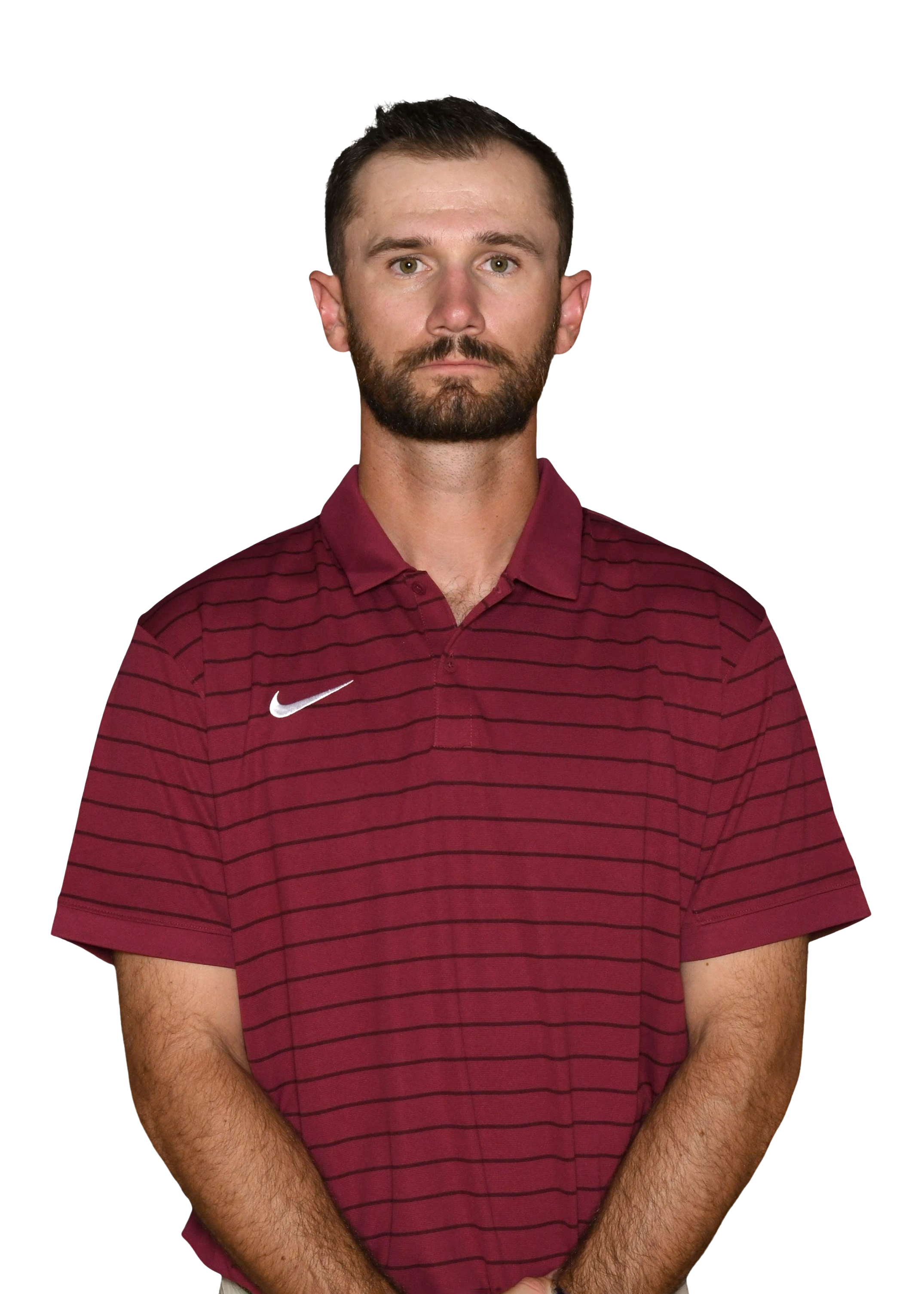 A man with short brown hair, a beard, and light skin is wearing a maroon and black striped polo shirt with a Nike logo. He has a serious expression and is standing against a black background.