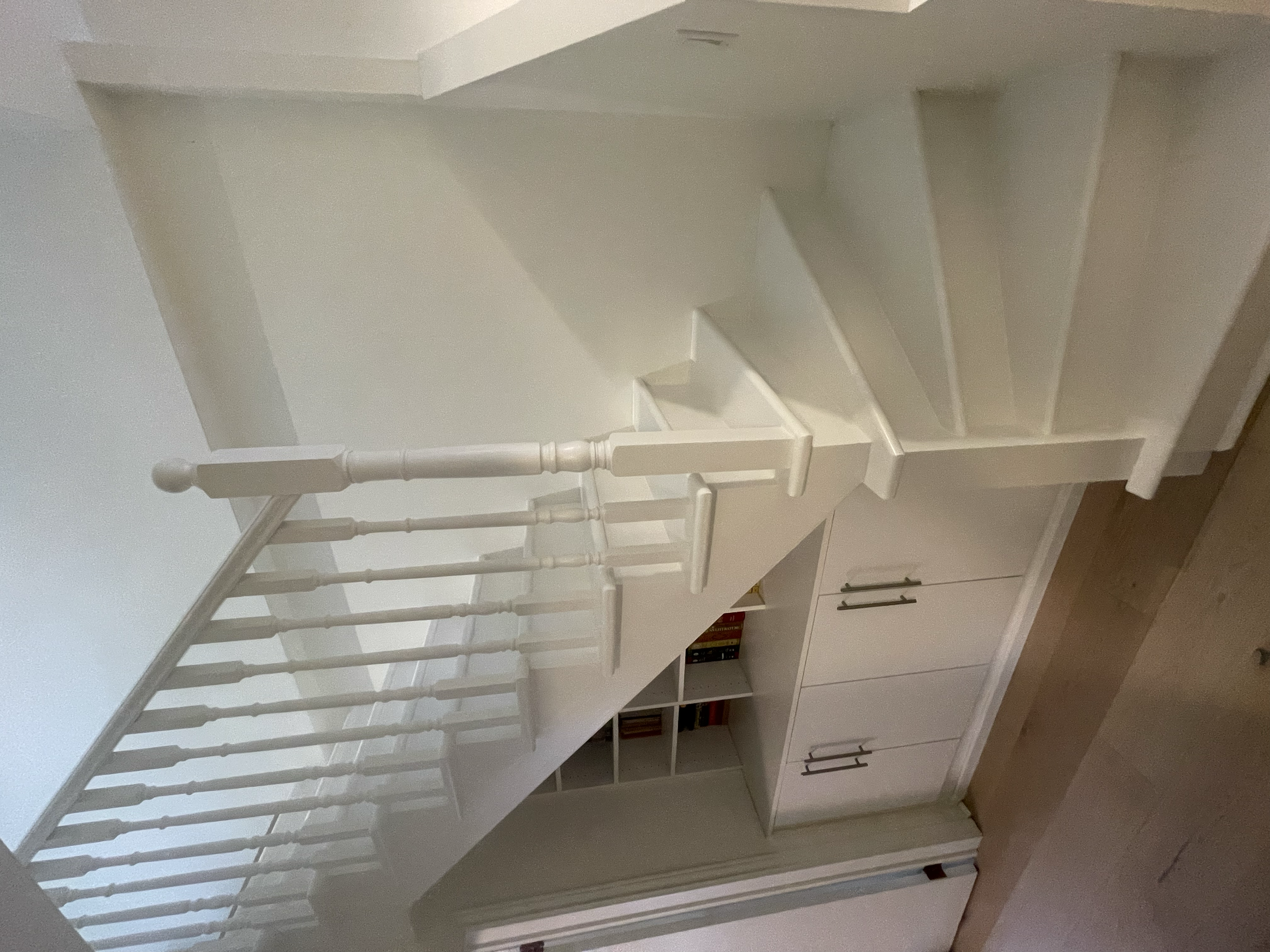 Part of a white staircase with painted spindle railing, Interior House Painting. Heather Feather Painting and Design. Toronto. Stair Refinishing.