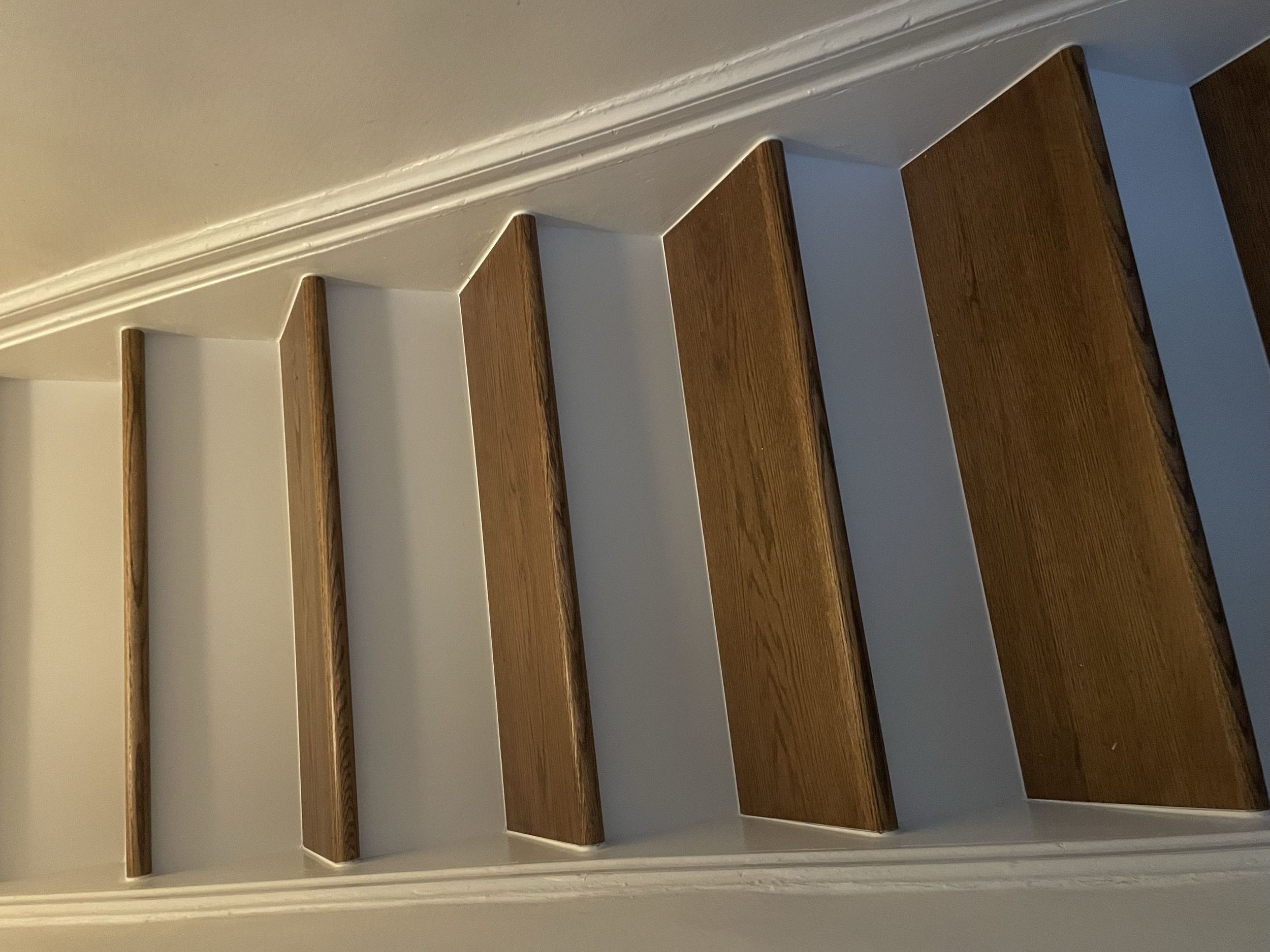 A staircase with wooden steps and white risers viewed from the bottom up. Interior House Painting. Heather Feather Painting and Design. Toronto. Stair Refinishing.