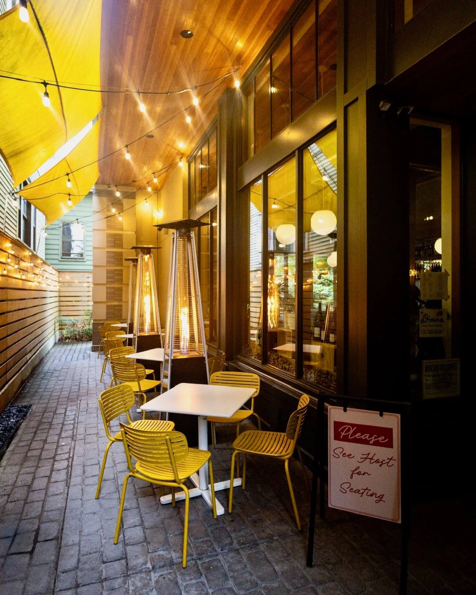 Covered patio seating with bistro tables, string lights and outdoor heaters.