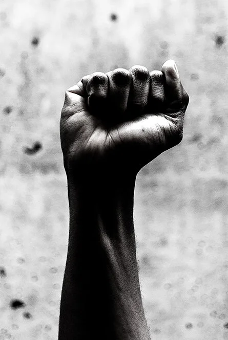 Black and white photo of a black person's fist raised in the air.