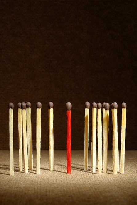 Fourteen upright and unlit beige matches, with a single red upright and unlit match in the center.