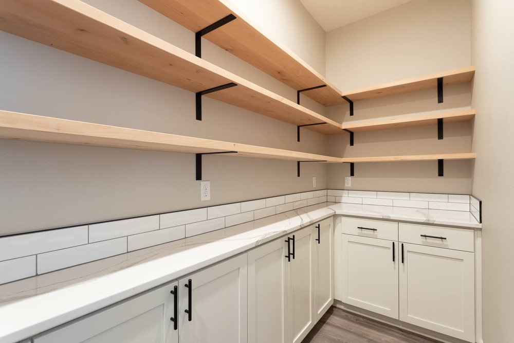 large walk in pantry with shelving and white cabinets