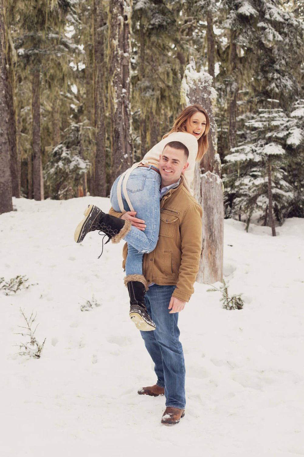engaged man with fiancé over his shoulder in the snow