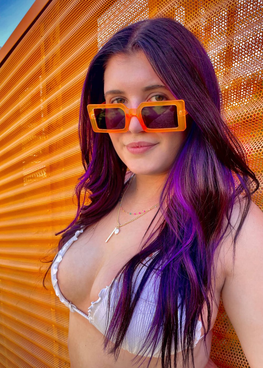 young woman with purple hair poses in front of orange wall in Palm Springs, California