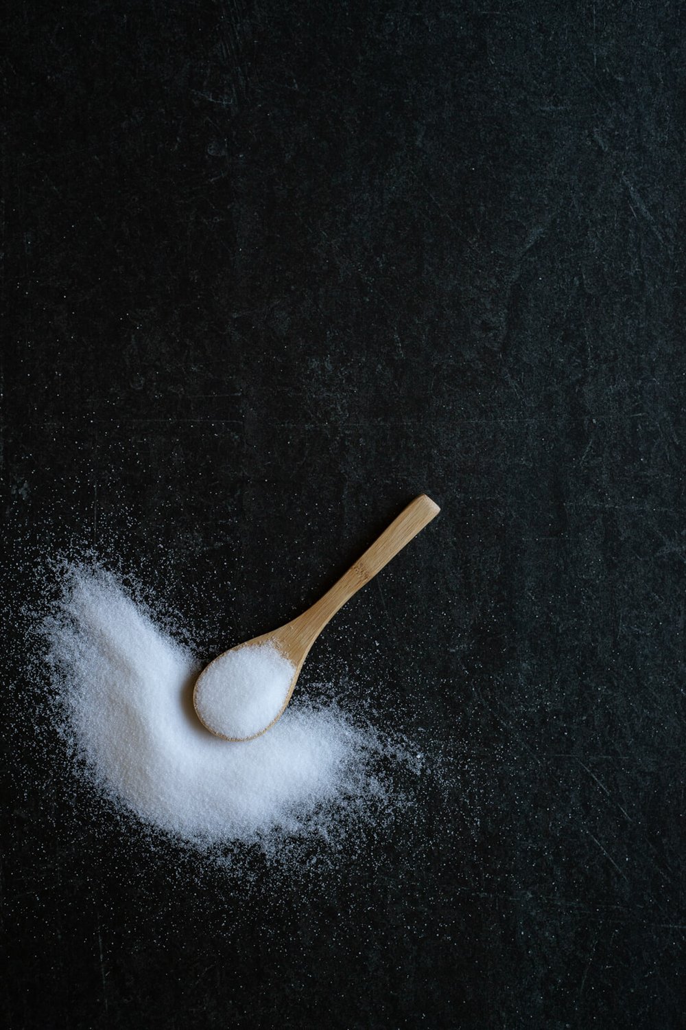 salt and wooden spoon on dark background