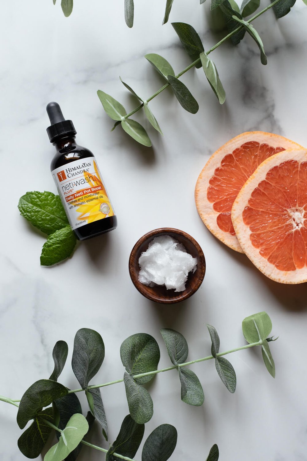 flat lay of netiwash with grapefruit, peppermint, eucalyptus, and coconut oil