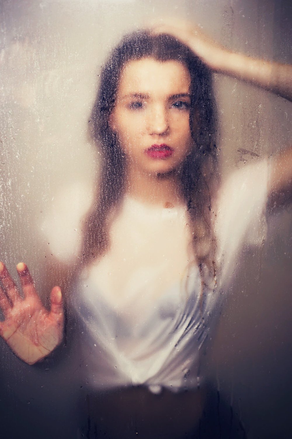 woman with red lipstick in shower behind wet glass