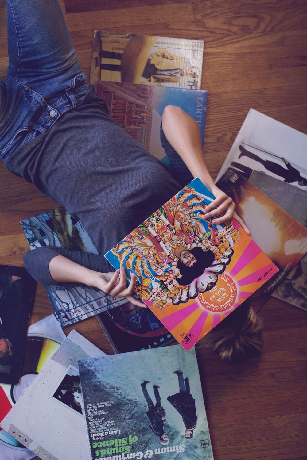 woman surrounded by records covering her face with jimi hendrix record
