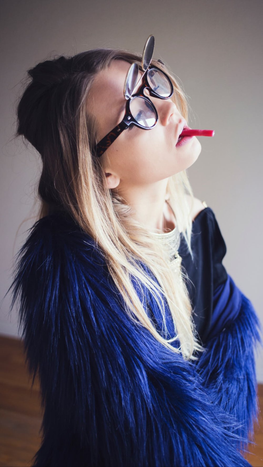 woman in fur coat and glasses using candy as a cigarette