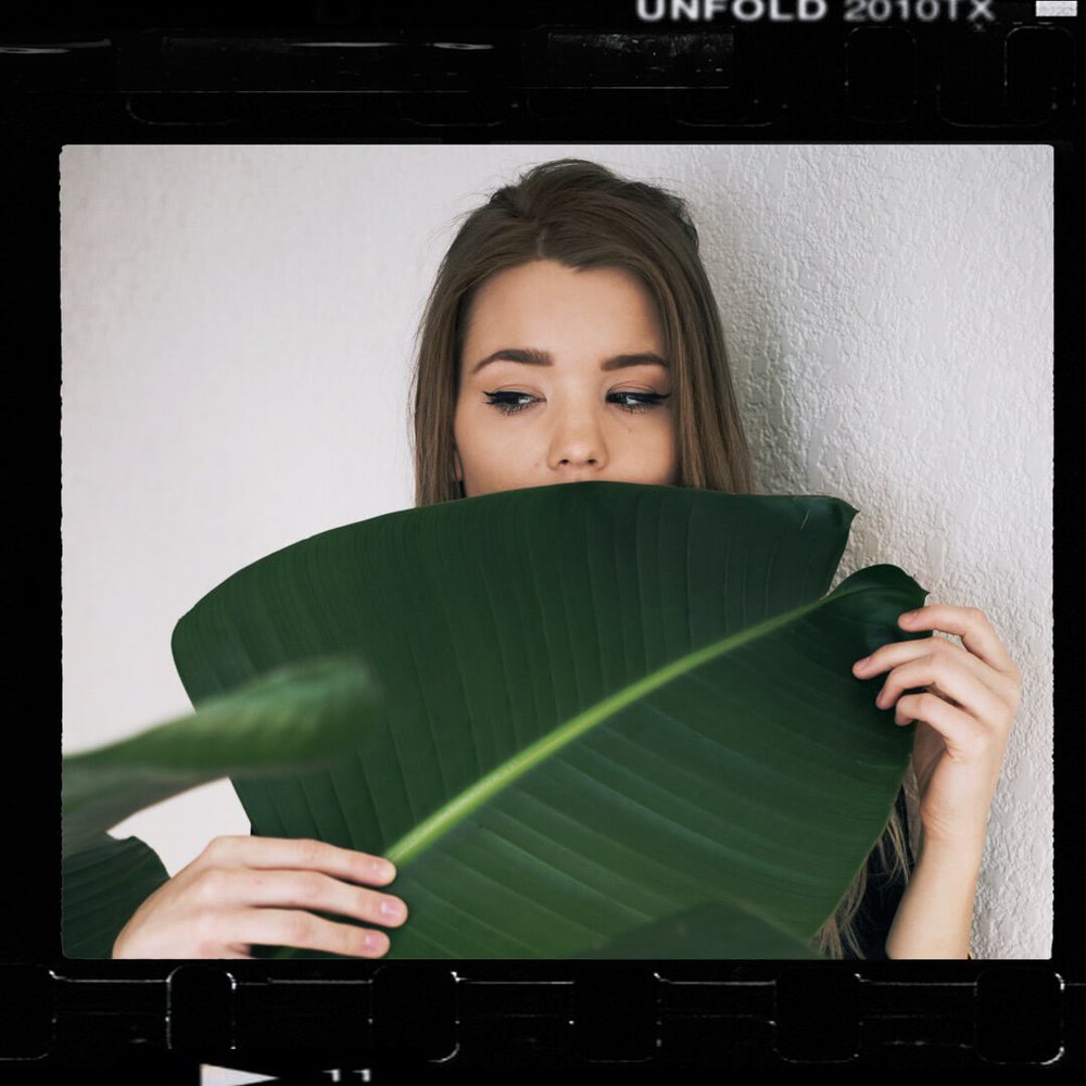 film scan of woman hiding behind palm leaf