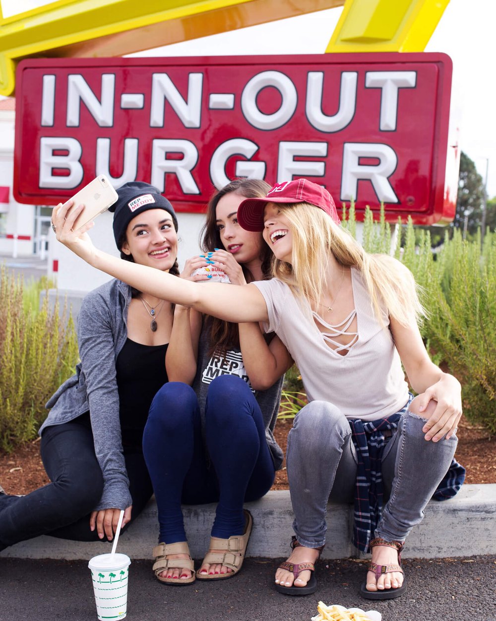 three girls wearing rep meddy take selfie in front of in n out burger sign