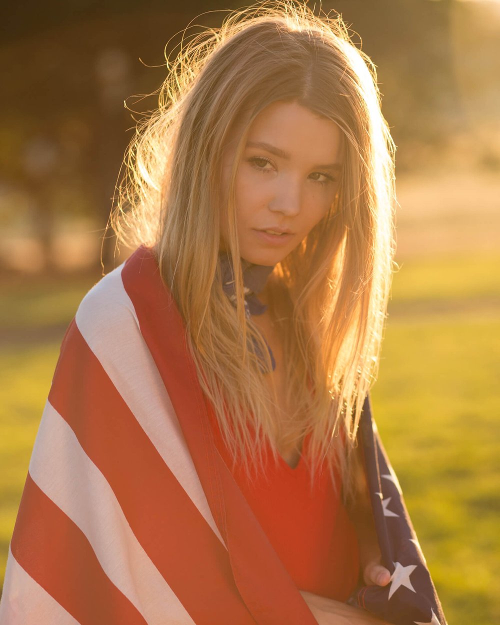 blonde woman wearing united states flag at golden hour