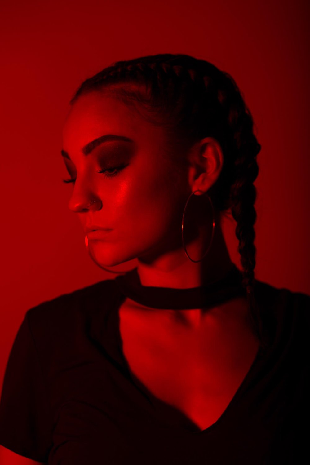 girl with braids and hoop earrings posing in red light