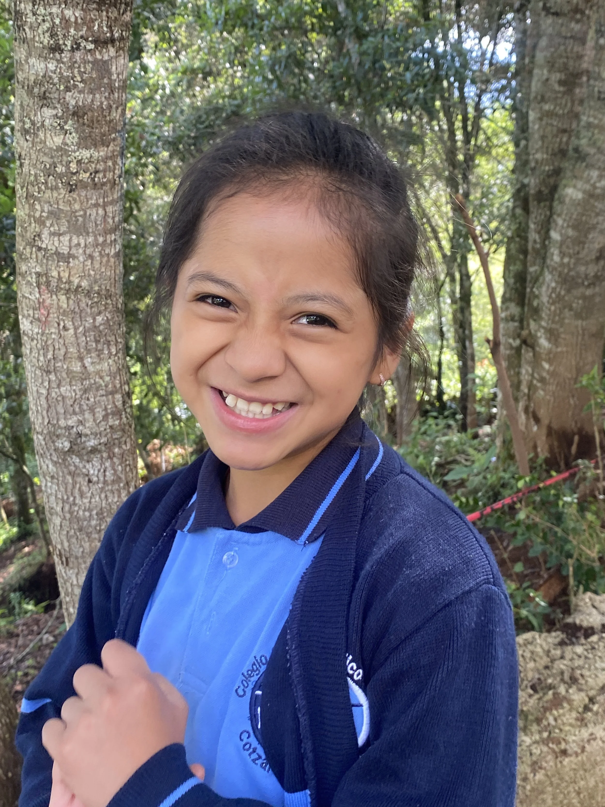 Colegio Horeb student smiling outdoors on school campus in San Juan Cotzal, Guatemala