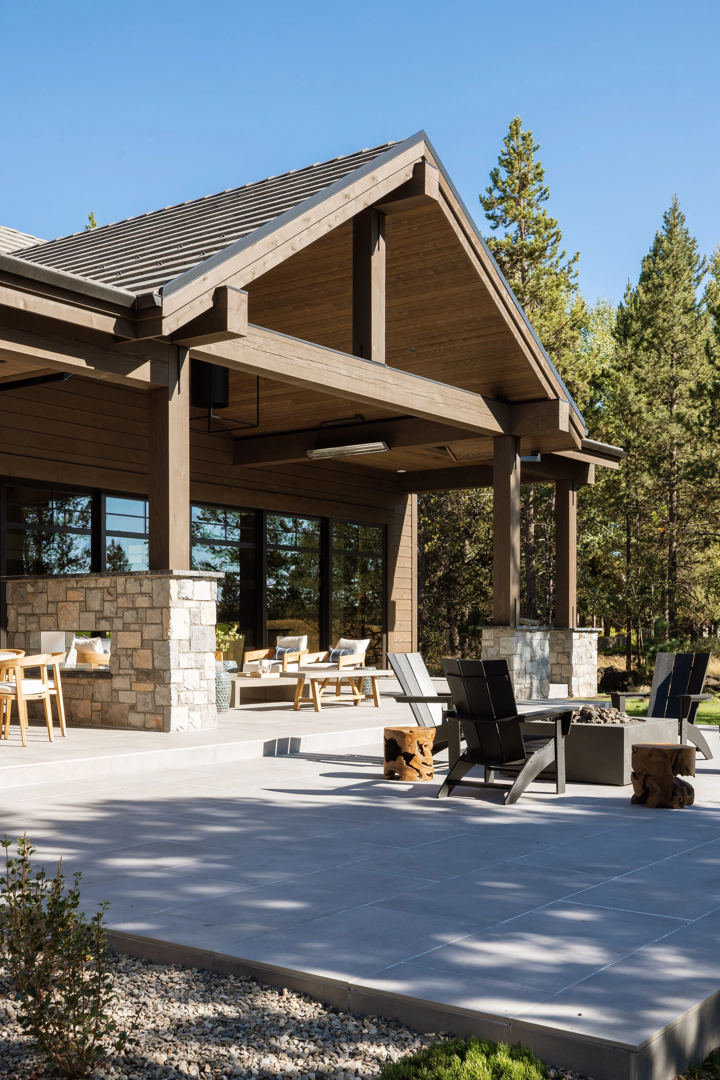 Covered patio under a timber gable with a fire pit and lounge seating.