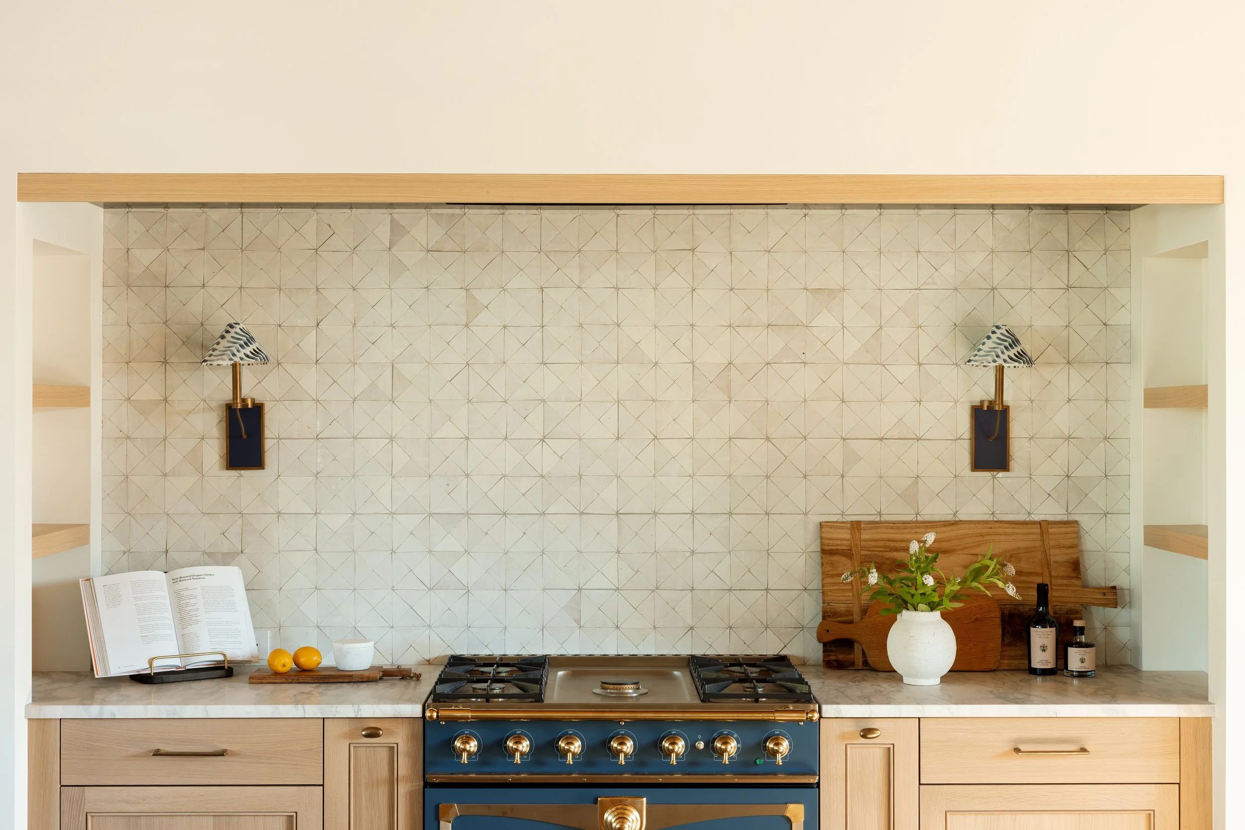 Kitchen range set in a tiled alcove with wall sconces.