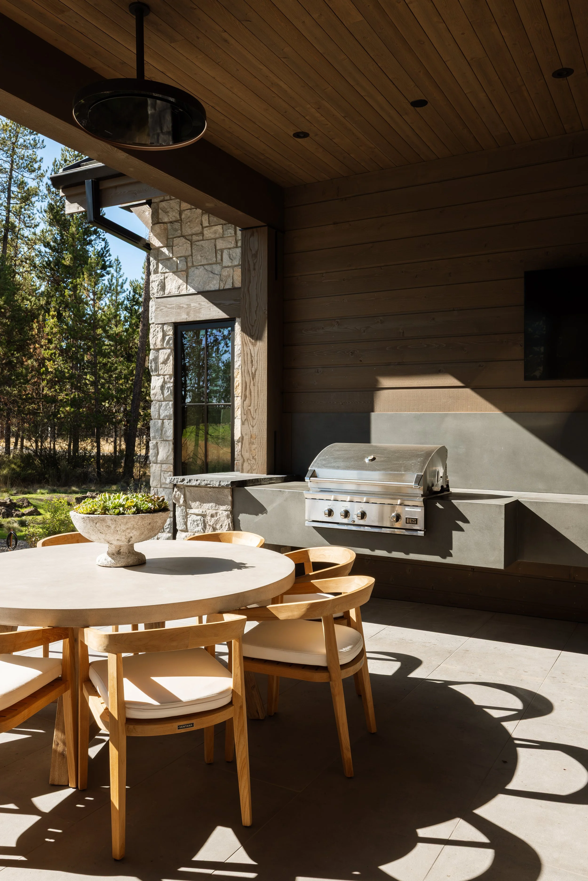 Covered outdoor kitchen with a built-in grill and dining table.