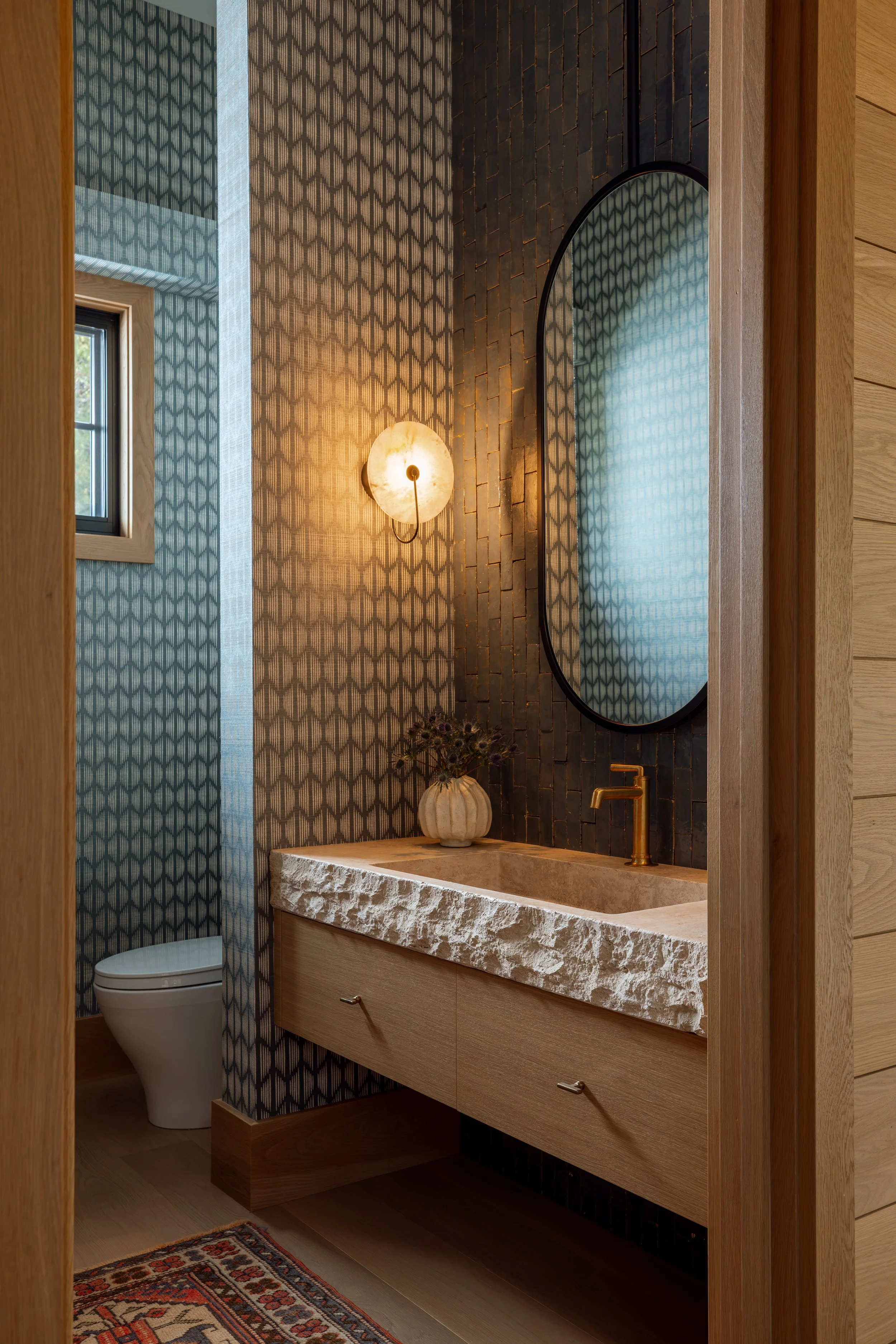 Powder room with a carved stone sink on a floating wood vanity.