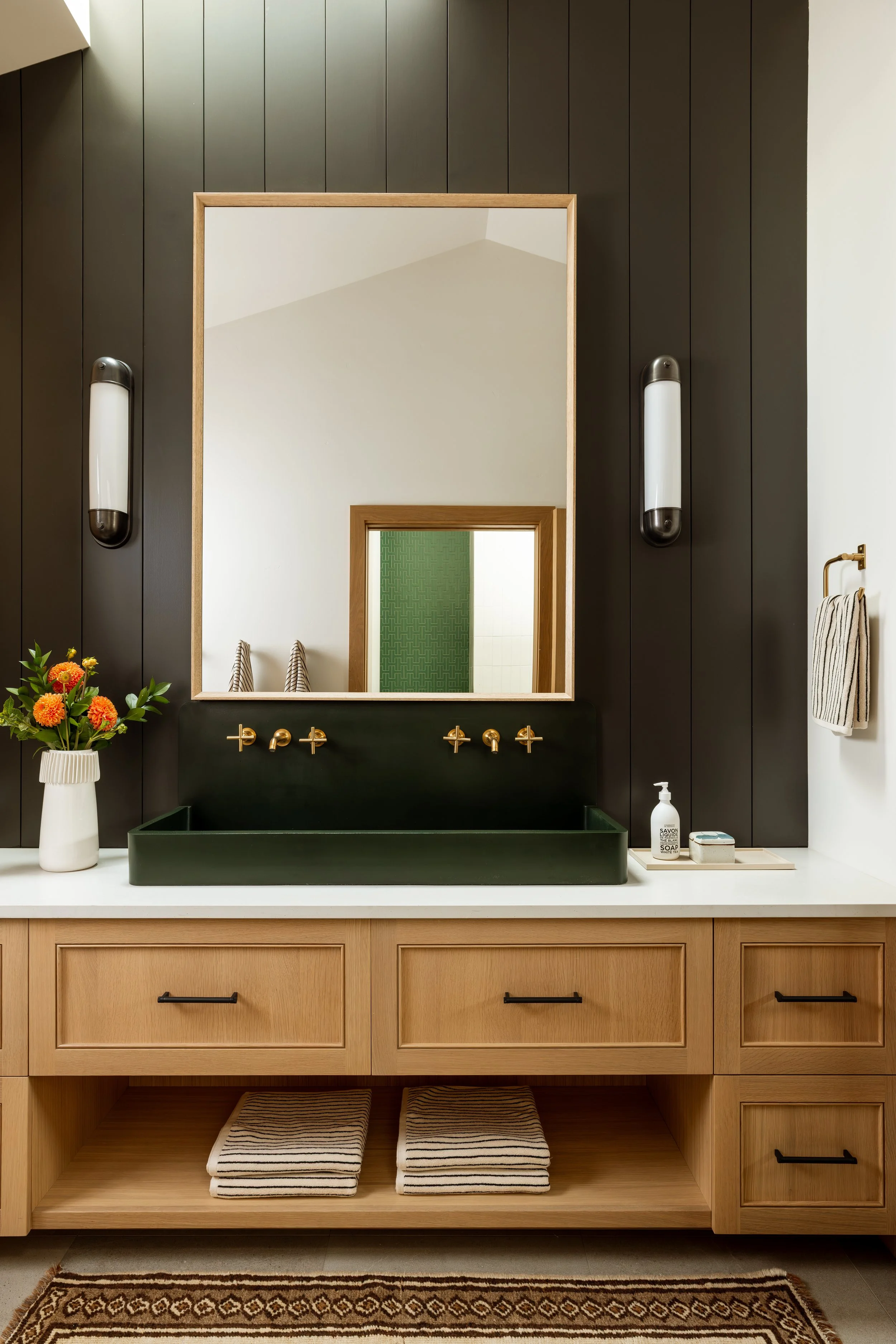 Bunk room bathroom with a dark shiplap wall, green trough sink and wood vanity.