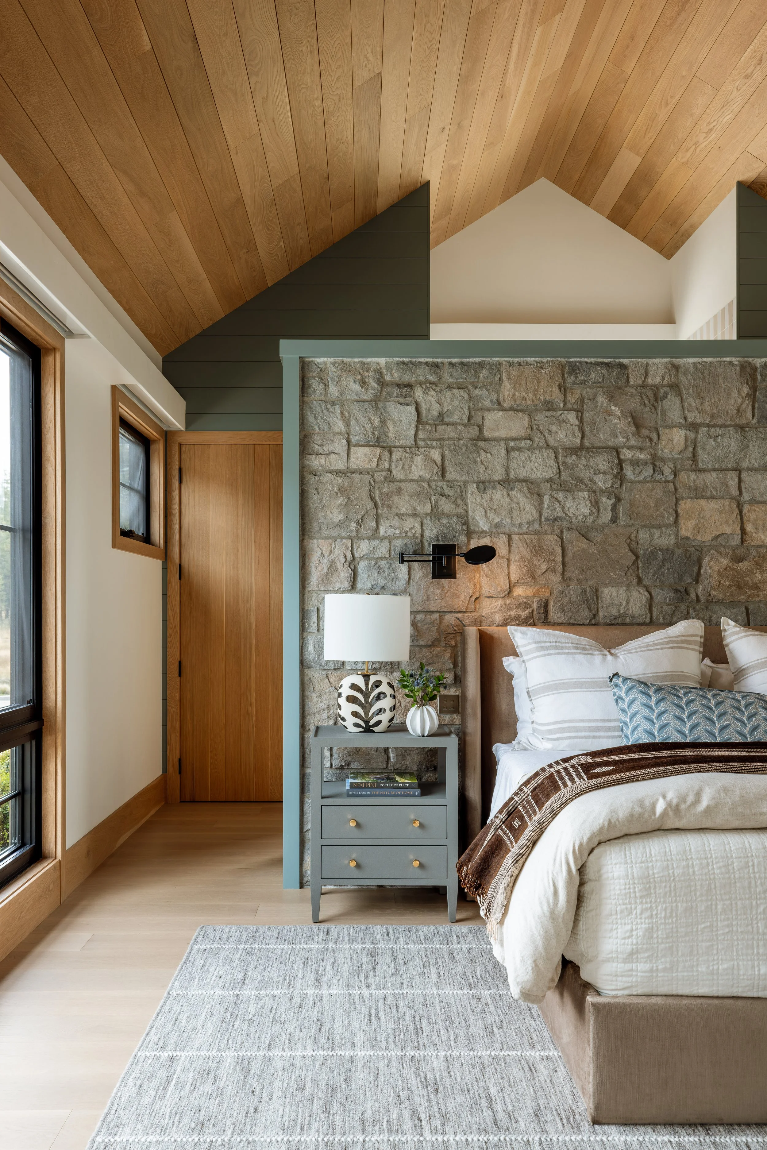 Bedroom with a stone accent wall and wood plank ceiling.